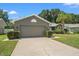 View of the house with a two car garage, lawn, and landscaping at 10032 Basin St, New Port Richey, FL 34655