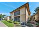 Exterior of a two story condo building featuring a screened porch and manicured landscaping under a clear blue sky at 10195 Sailwinds N Blvd # 208, Largo, FL 33773