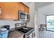 Efficient kitchen featuring stainless steel microwave and range, wood cabinets, and view to screened porch at 10195 Sailwinds N Blvd # 208, Largo, FL 33773