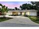 Charming one-story home with white siding, a spacious driveway, and lush landscaping at dusk at 10265 130Th St, Largo, FL 33774