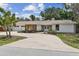 Charming one-story home with white siding, a spacious driveway, and lush landscaping in the daylight at 10265 130Th St, Largo, FL 33774