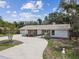 Exterior view of the home with a long driveway, 2-car garage and mature trees at 10265 130Th St, Largo, FL 33774