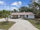 Exterior elevation featuring a curved driveway, attached 2-car garage and mature landscaping at 10265 130Th St, Largo, FL 33774