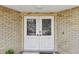 Close-up of the double front doors featuring decorative glass inserts and brick surround at 10265 130Th St, Largo, FL 33774