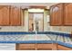 Close-up of a kitchen sink area showcasing blue tiled countertops, wood cabinets, and natural light at 10265 130Th St, Largo, FL 33774