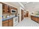 Bright kitchen with wood cabinets, white appliances, tiled countertops, and a view into the dining area at 10265 130Th St, Largo, FL 33774