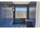Unique walk-in shower showcasing contemporary blue tile work, stylish fixtures, and a window at 10265 130Th St, Largo, FL 33774