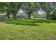 Spacious backyard with green grass, mature trees, and a view of the property and surrounding homes at 11001 Ridgedale Rd, Temple Terrace, FL 33617