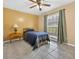 Bright bedroom features a ceiling fan, window with green curtains, and a vintage side table with a lamp at 11001 Ridgedale Rd, Temple Terrace, FL 33617