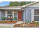 Charming home featuring a red door, brick facade, and lush landscaping at 11001 Ridgedale Rd, Temple Terrace, FL 33617