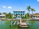 Back of a two-story blue home on a waterway showing a dock, boat lift, and backyard pool at 11260 7Th E St, Treasure Island, FL 33706