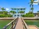 Stunning three-story blue waterfront home with multiple balconies and a private dock on a sunny day at 11260 7Th E St, Treasure Island, FL 33706