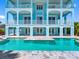 Stunning light-blue three-story waterfront home with balconies and a refreshing private pool and patio at 11260 7Th E St, Treasure Island, FL 33706