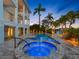 Backyard area at dusk showing a pool and spa next to a blue two-story home with multiple balconies at 11260 7Th E St, Treasure Island, FL 33706