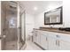 Bright bathroom with tile flooring, white cabinets, granite countertop, framed mirror, and enclosed glass shower at 1150 Tarpon Center Dr # 1D, Venice, FL 34285