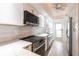 Modern kitchen featuring stainless steel appliances, gray tile backsplash, and white cabinets at 1150 Tarpon Center Dr # 1D, Venice, FL 34285