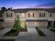 Exterior view of townhomes with a tree, individual garages, and tan facade under a dusk sky at 11916 Castine St, New Port Richey, FL 34654
