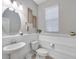 Stylish half bathroom with updated lighting, framed oval mirror, and a decorative wall panel at 12025 Greengate Dr, Hudson, FL 34669
