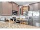 Open shelving shows off dishes in this kitchen with mocha cabinets, stainless steel, and granite counters at 12025 Greengate Dr, Hudson, FL 34669