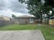Back of the house features a simple brown exterior, lawn, mature trees, and a concrete pad at 1309 29Th S St, St Petersburg, FL 33712