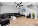 Spacious living room with a black leather sectional, a modern ceiling fan, and tile flooring, providing a stylish and comfortable area at 1601 Fox Grape Loop, Lutz, FL 33558