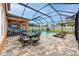 View of the screened-in patio with outdoor seating, dining, and pool with relaxing lounge chairs at 1601 Fox Grape Loop, Lutz, FL 33558