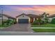 Charming single-story home featuring a tile roof, paved driveway, and lush tropical landscaping at dusk at 20828 Cattail Blvd, Venice, FL 34292