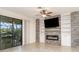 Living room featuring a stone accent wall with a fireplace, built-in shelving, and a sliding glass door at 20828 Cattail Blvd, Venice, FL 34292