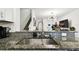 Granite countertops, stainless steel sink, and modern fixtures in a well-lit kitchen space with stairs and living area beyond at 2513 Sunray Venus Way, Ruskin, FL 33570