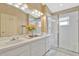 Bright bathroom featuring a double sink vanity, a glass enclosed shower, and updated lighting fixtures at 26616 Whirlaway Ter, Wesley Chapel, FL 33544