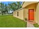Warm and inviting single-story home featuring a vibrant orange front door and lush green lawn at 26616 Whirlaway Ter, Wesley Chapel, FL 33544
