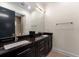Modern bathroom with dual sinks, dark wood cabinets, a large mirror, and tile flooring at 2711 W Trilby Ave, Tampa, FL 33611