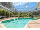 Sparkling screened-in pool surrounded by lush tropical landscaping and a brick paver deck at 2800 Resnik W Cir, Palm Harbor, FL 34683