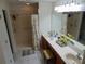 Bathroom with dual sinks, vanity, and accessible walk-in shower with curtain and grab bars at 29413 Caddyshack Ln, San Antonio, FL 33576