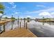 Wooden dock on a calm canal reflecting the blue sky and clouds, offering waterfront access to the home at 4252 Floramar Ter, New Port Richey, FL 34652