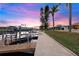 Scenic waterfront view featuring a private dock with boat lift on a calm canal at sunset with pink and blue skies at 4252 Floramar Ter, New Port Richey, FL 34652