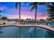 Backyard pool area with palm trees, waterfront view and colorful dusk skies creating a serene oasis at 4252 Floramar Ter, New Port Richey, FL 34652