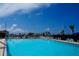 Community swimming pool on a sunny day, showcasing lounge chairs and tall masts of sailboats in the background at 4252 Floramar Ter, New Port Richey, FL 34652