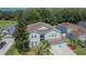 Aerial view of a two-story house in a residential area, with a three-car garage, manicured lawn, and mature palm tree at 4634 Mapletree Loop, Wesley Chapel, FL 33544