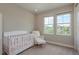 This Bedroom features a white crib and chair with two windows that provide natural light at 4644 San Martino Dr, Wesley Chapel, FL 33543