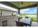 Outdoor kitchen with a built-in grill, sink, and dining area overlooking the tranquil lake at 4644 San Martino Dr, Wesley Chapel, FL 33543
