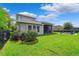 View of a lush backyard featuring a screened lanai and a cozy fire pit area with Adirondack chairs at 6007 Quartz Lake Way, Lithia, FL 33547
