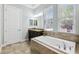 Bathroom featuring a soaking tub with tiled surround and dual-sink vanity next to a door and windows at 6007 Quartz Lake Way, Lithia, FL 33547
