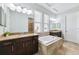 Bright bathroom features dual sinks with granite counters and large soaking tub next to light-filled windows at 6007 Quartz Lake Way, Lithia, FL 33547