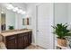 Bathroom includes a vanity with granite countertop and a large mirror, next to a white paneled door at 6007 Quartz Lake Way, Lithia, FL 33547