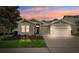 Charming single-story home with a well-manicured lawn and a two-car garage under a vibrant sunset sky at 6007 Quartz Lake Way, Lithia, FL 33547