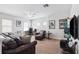 Spacious living room with neutral carpet and walls, ceiling fan, leather couches, and a television viewing area at 6007 Quartz Lake Way, Lithia, FL 33547