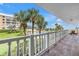 Balcony view overlooking the community pool and manicured grounds, extending to the ocean in the distance at 6600 Sunset Way # 118, St Pete Beach, FL 33706
