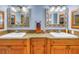 Bathroom featuring dual sinks, wood cabinets, and decorative mirrors at 6600 Sunset Way # 118, St Pete Beach, FL 33706