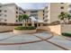 Inviting condo entrance featuring a circular driveway, lush landscaping, and a well-maintained facade at 6600 Sunset Way # 118, St Pete Beach, FL 33706
